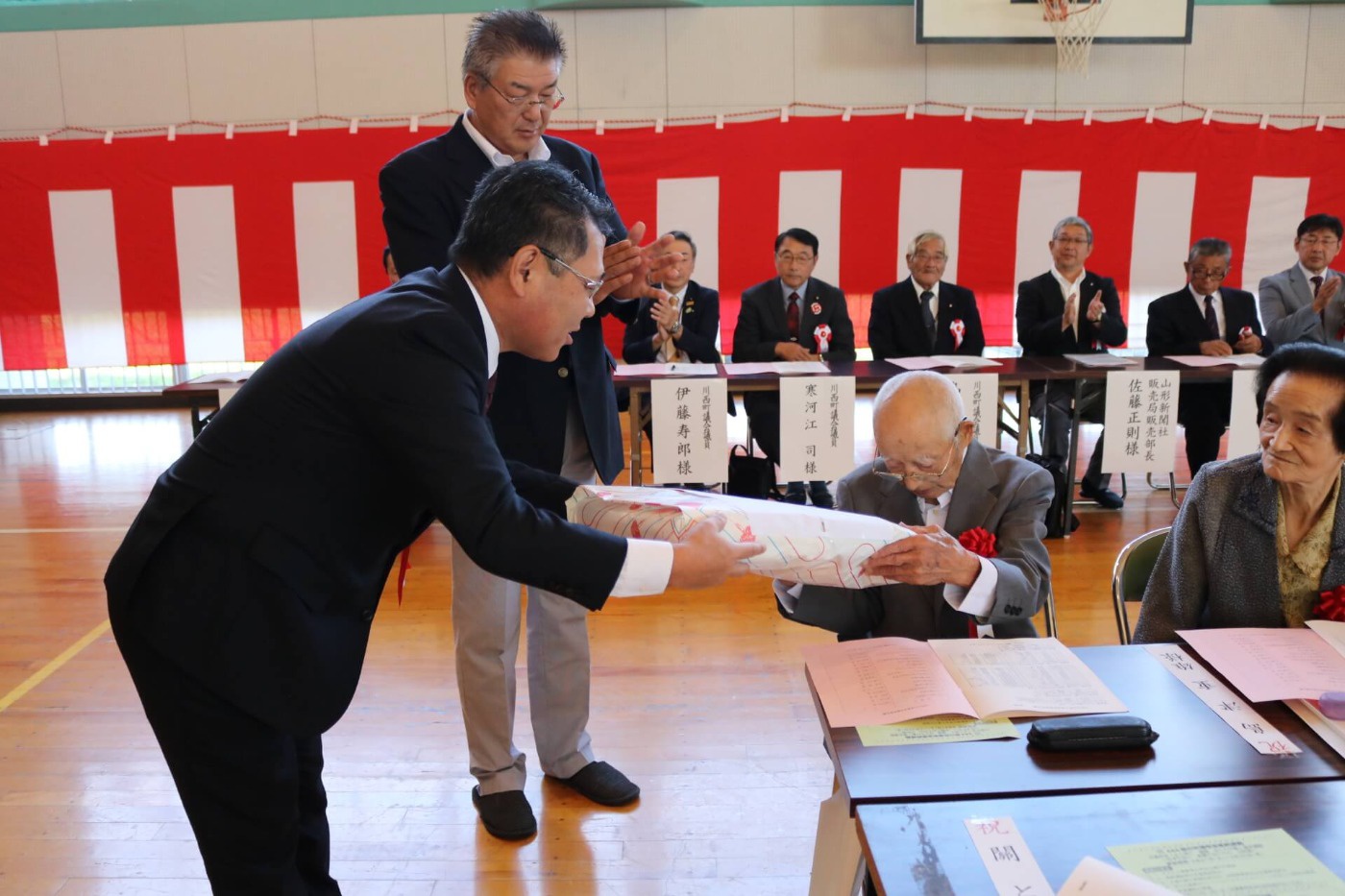 川西町と地区社協推進委員会からの記念品が贈呈されている様子