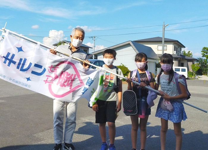 写真：キラリかけ愛運動の旗を持った小学生と（特）きらりよしじまネットワーク理事長