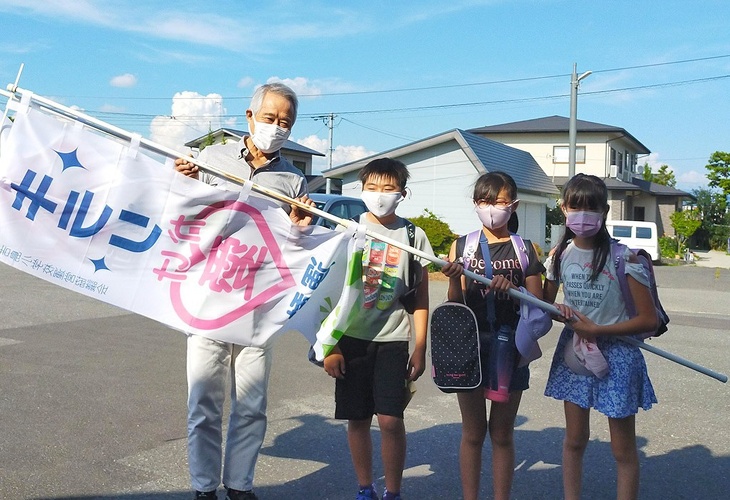 写真:キラリかけ愛運動の旗を持った小学生と(特)きらりよしじまネットワーク理事長