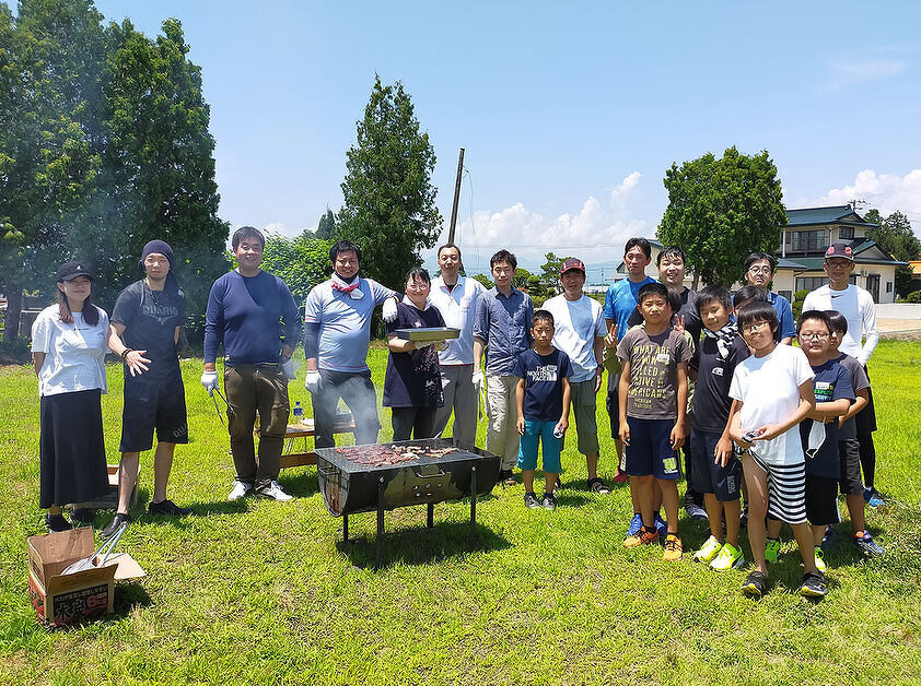 写真：児童クラブきらり：晴天のもとバーベキューを行っている